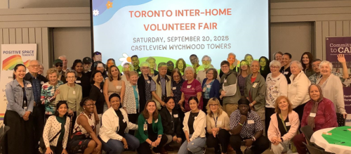 A large group of people posing together in front of a presentation screen at Castleview Wychwood Towers. The screen displays the text: “TORONTO INTER-HOME VOLUNTEER FAIR, Saturday, September 20, 2025.” The group is standing and kneeling in rows.