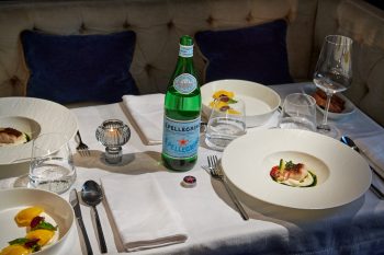A table at a restaurant set up with white linen and plated dished.