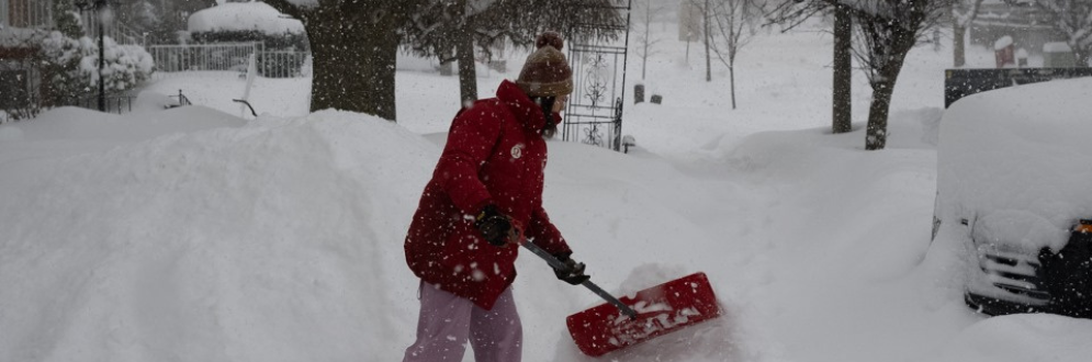 A woman shoveling a sidewalk during a winter storm in Toronto.