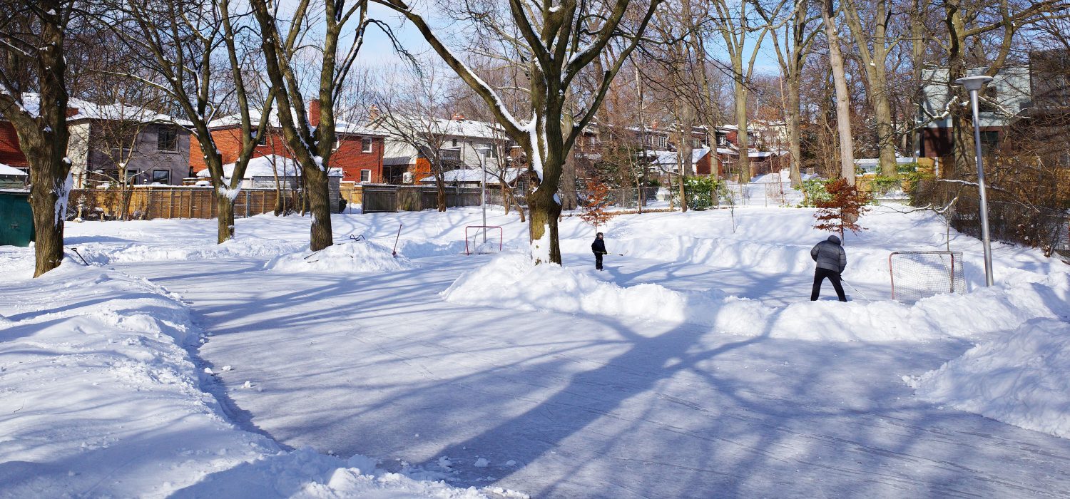 Love Crescent Parkette Natural Ice Rink with children playing hockey, surrounded by snow-covered trees and homes.