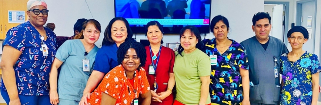 A group of staff stand together in a bright room, wearing colourful scrubs in various patterns and solid colours.