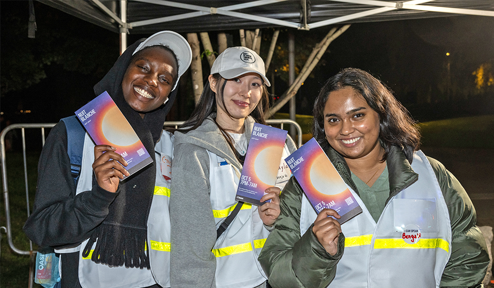 hree volunteers smiling at the camera and holding pamphlets