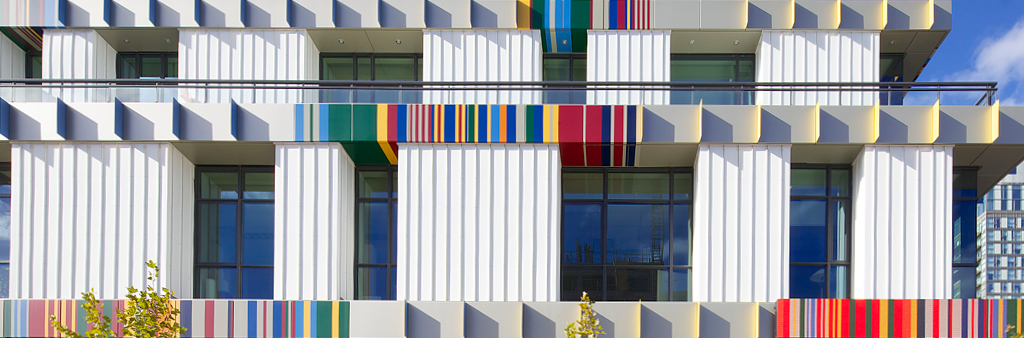 Close up of an exterior of a white building with windows and bands of colour