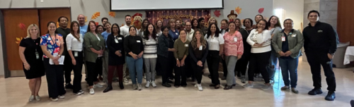 Staff pose for a photo in front of a projector screen as part of RSA Days