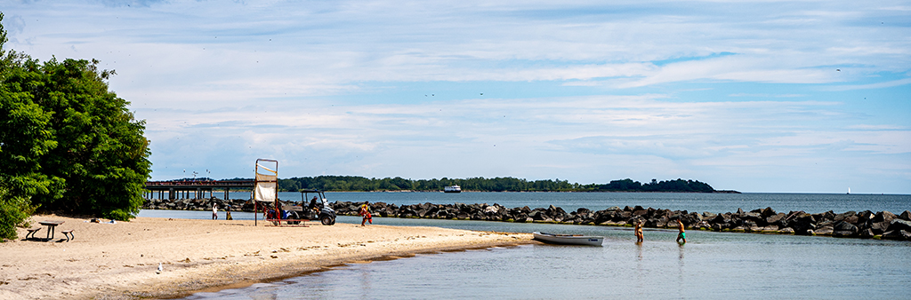 Beach area with a small boat and 2 people standing the water