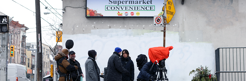 A film crew working outside of a corner store.