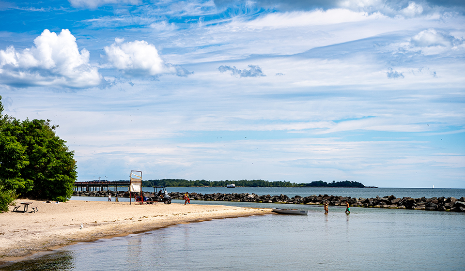 Beach area with a small boat and 2 people standing the water