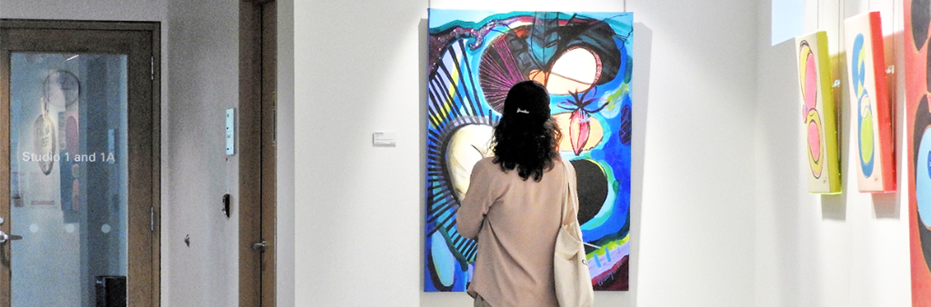Visitor viewing at colourful paintings in art gallery.