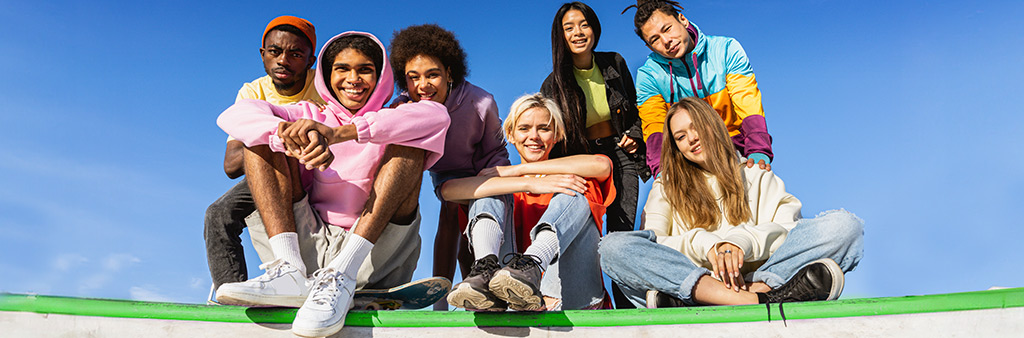 A diverse group of youth sitting outside in the sun posing as a group.