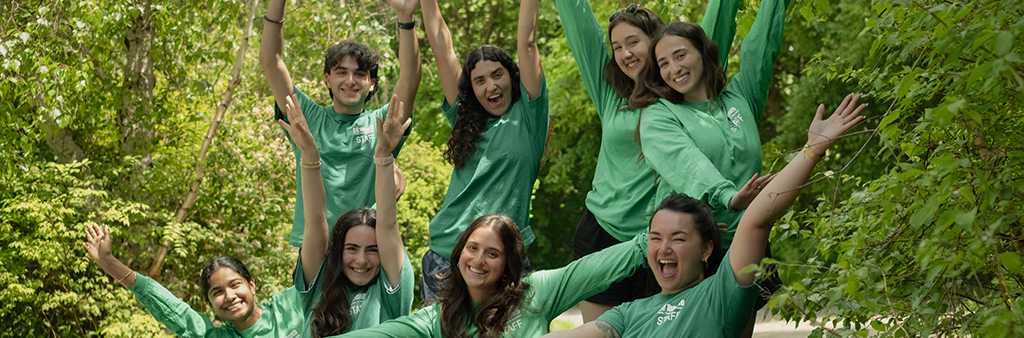 A group of people in green City of Toronto staff shirts standing in a tree lined path.