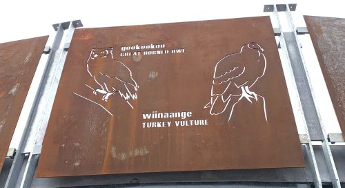 Bridge facade reading gookookoo great horned owl with text below reading wiinaange turkey vulture and two birds on either side
