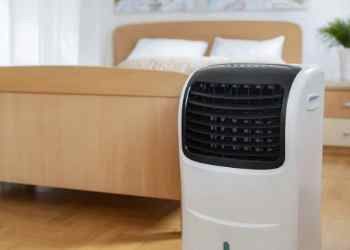 Portable air conditioner with white and black exterior in a bedroom.