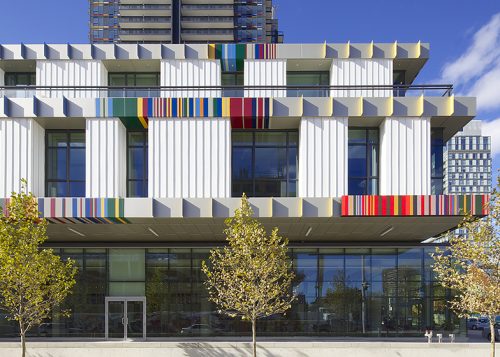 Close up of an exterior of a white building with windows and bands of colour