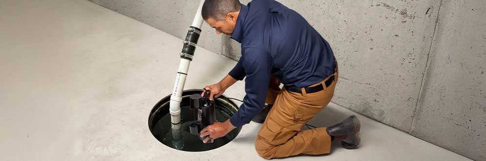 A person setting up a sump pump in a basement