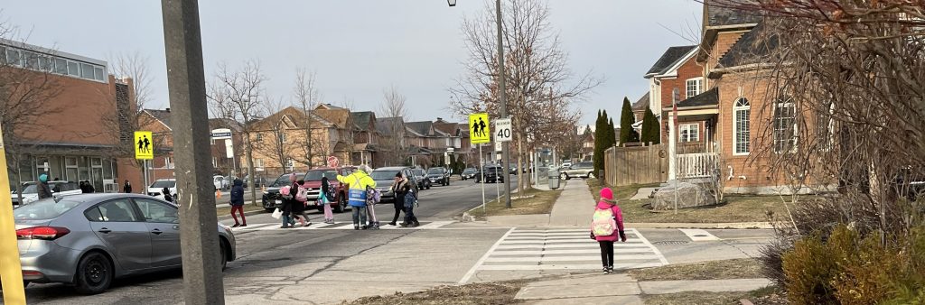 Morning school crossing with students and crossing guard.