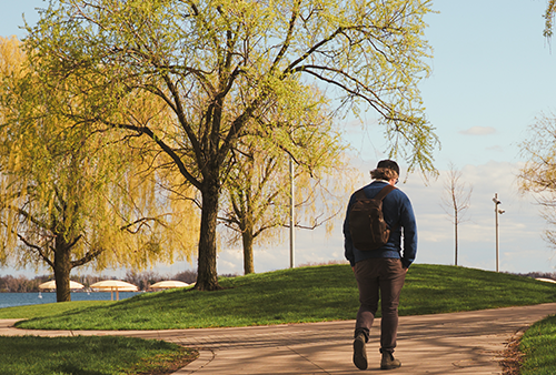 A person walking through a park on a paved path.