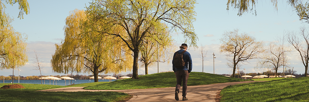 A person walking through a park on a paved path.