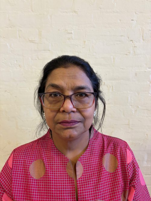 Headshot photograph of a woman with glasses wearing pink blouse
