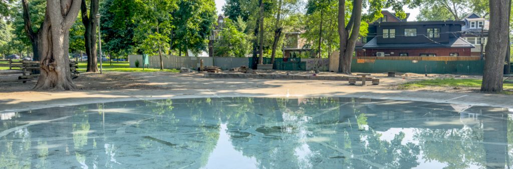 A wading pool under large trees at Dufferin Grove Park.