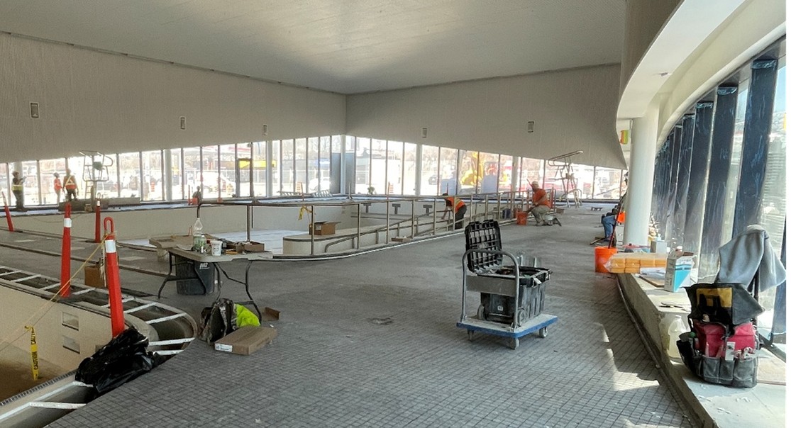A photograph of the pool area at Wallace Emerson Community Recreation Centre. Workers are actively laying small tiles on the pool deck area.