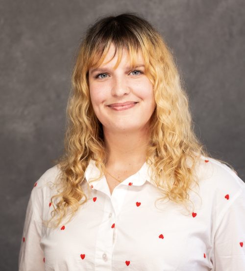 Headshot photograph of a woman wearing polka-dot button up shirt