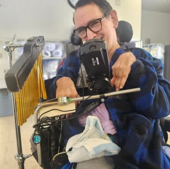 A resident wearing a blue and black sweater plays an instrument.