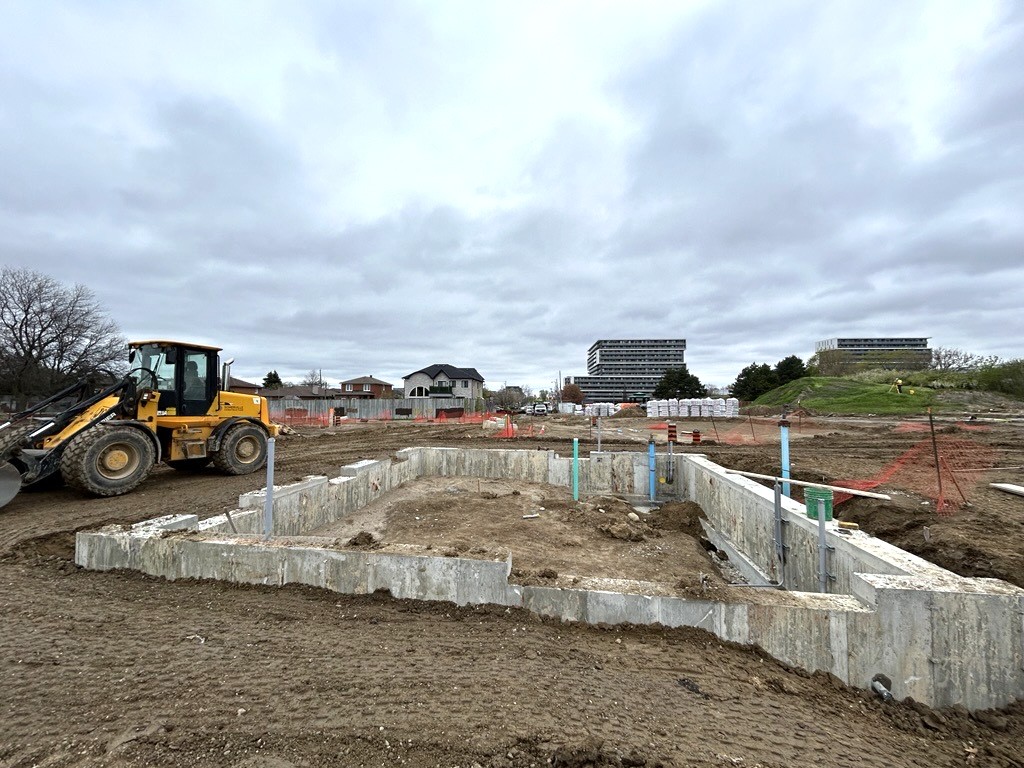 View of the completed building foundation walls with exposed plumbing and electrical connections.