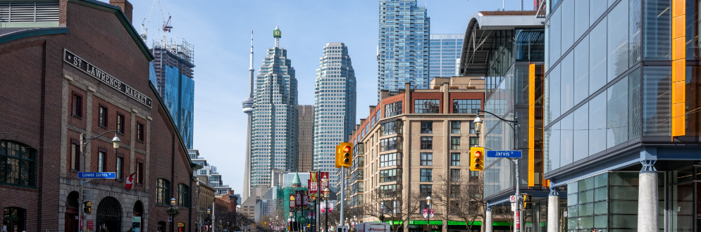 Image of St. Lawrence market on the south side of the street, with the north market visible as well. Downtown is in the background with the CN just poking out.