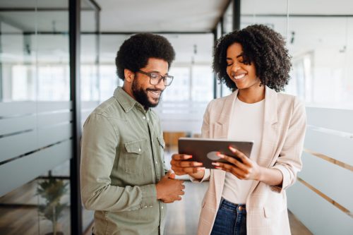 A man and a woman smiling look at a tablet.