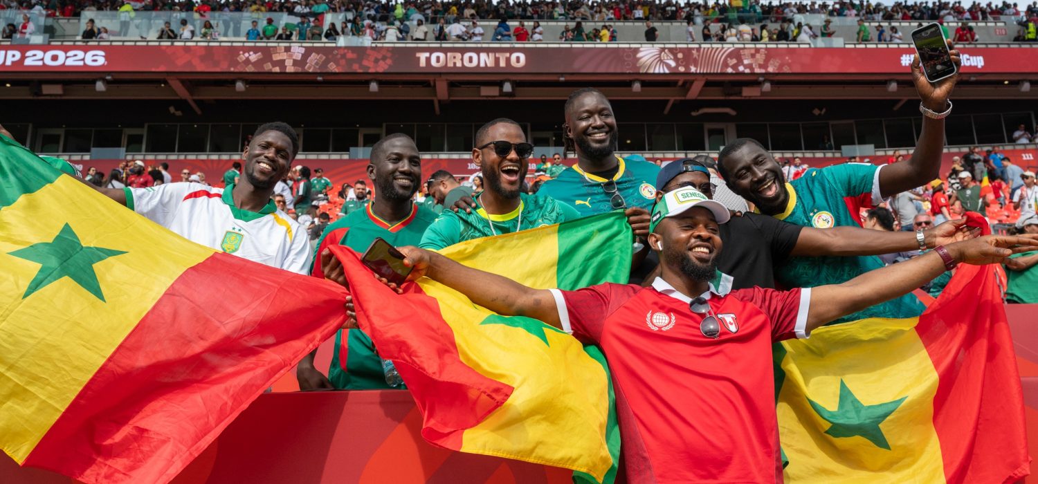Fans smile and show off Senegal flags in stadium seats