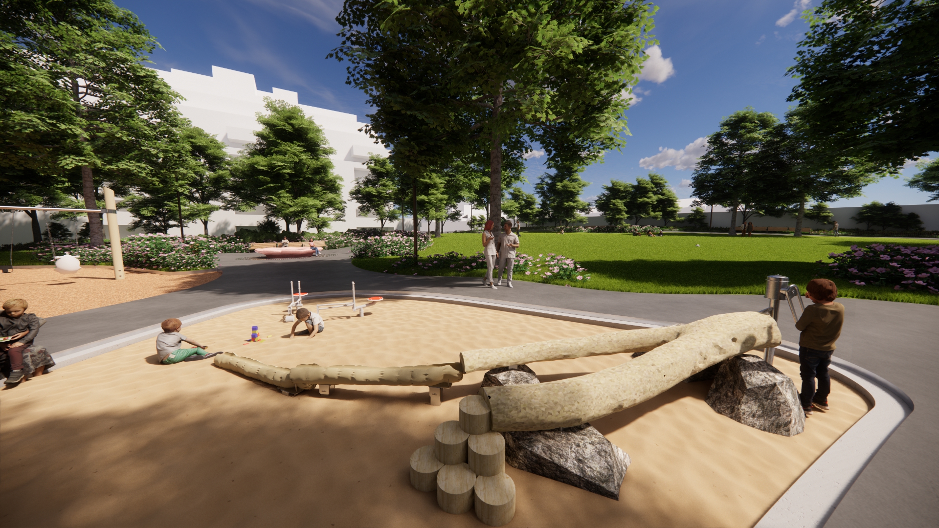View of a sand play area featuring a water play element designed to resemble a fallen tree trunk, along with miniature excavators where children are playing in the sand. In the background, a pathway leads toward the fountain area, framed by an open lawn and a canopy of mature trees.