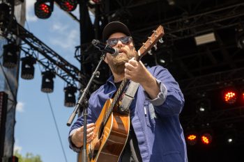 Musician sings into microphone and plays guitar