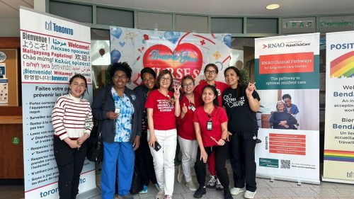 Group of staff standing together in front of a “Thank You Nurses” display and informational banners, posing for a photo.