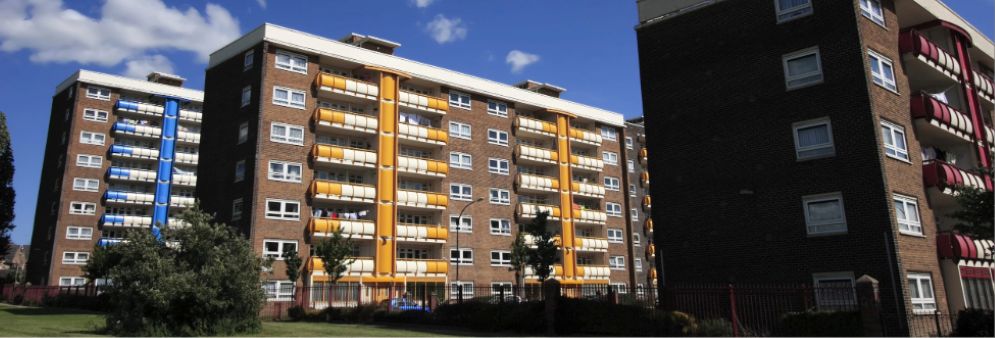 Mid-rise multi-unit residential apartment buildings under a blue sky.