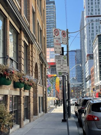 Street view showing a parking sign mounted below existing parking regulation signs on a utility pole.