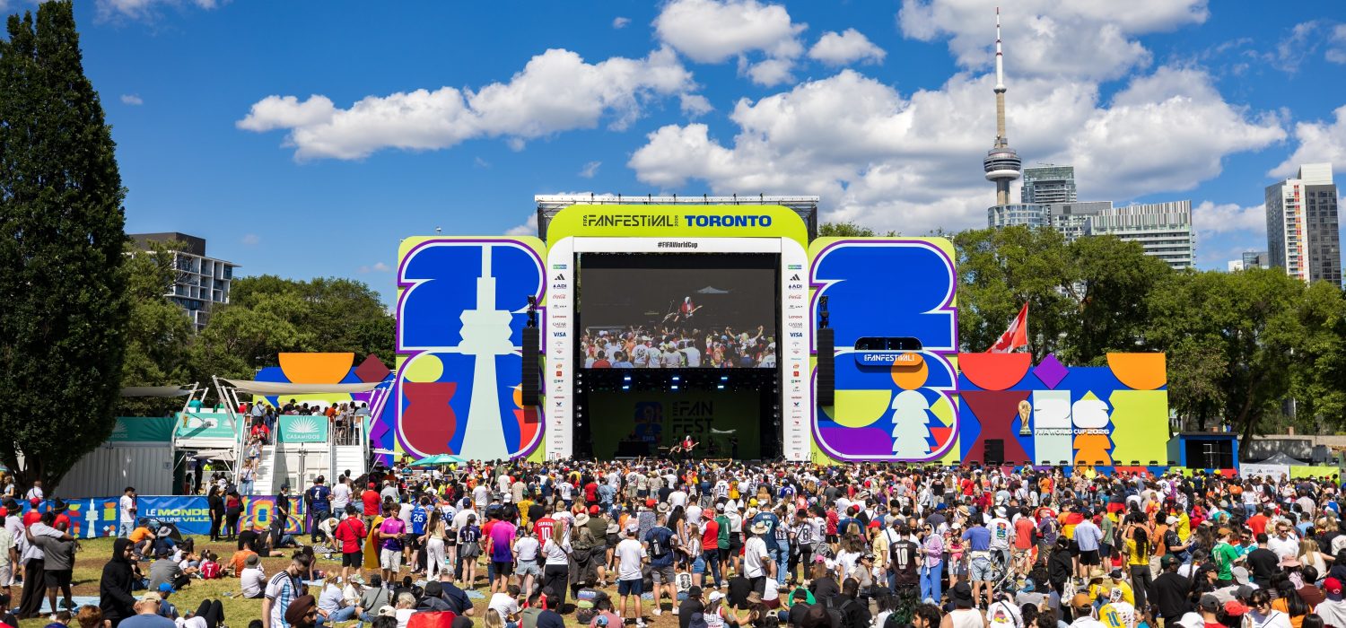 Audience looks towards Fan Festival stage with tv screen. Toronto skyline in the background