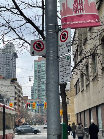 Street view showing a parking sign mounted below existing parking regulation signs on a utility pole.