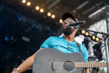 Musician on stage with guitar sings into microphone