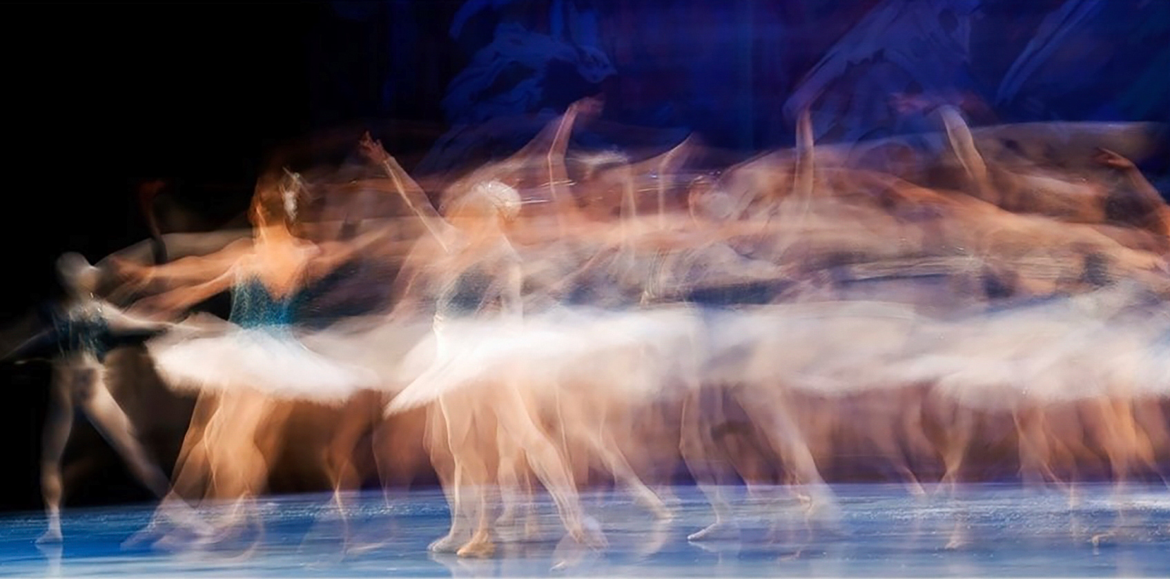 A ballerina moves across the stage in a blurred image.