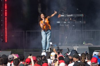 Musician sings into microphone and pianist in the background on stage in front of crowd