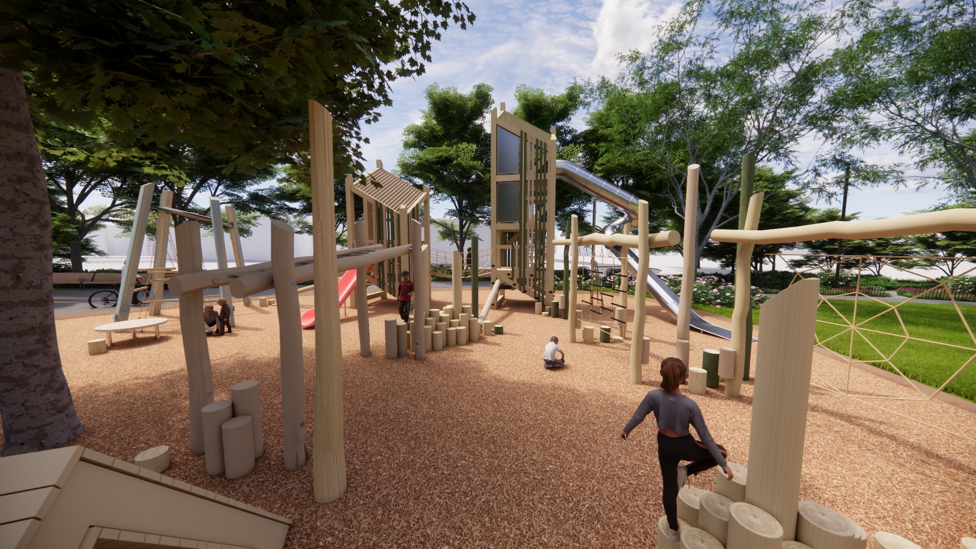 View from within the playground. Two large timber play towers rise above the play area and are connected by log stepping elements, a rope bridge, and a variety of climbing features. The structure includes both a lower slide and a larger tube slide, offering different play experiences for children of varying ages and abilities. Throughout the playground, monkey bars, overhead climbing elements, and other challenging features. A large mature tree is integrated directly into the playground, providing shade and creating a comfortable, nature-filled play environment.