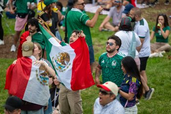 Fans cheering, some holding the flag of Mexico