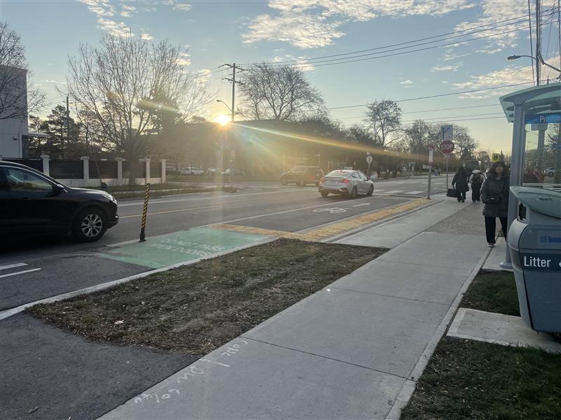 People wait by a raised bus stop that is integrated with a bike lane on Wilmington Avenue.