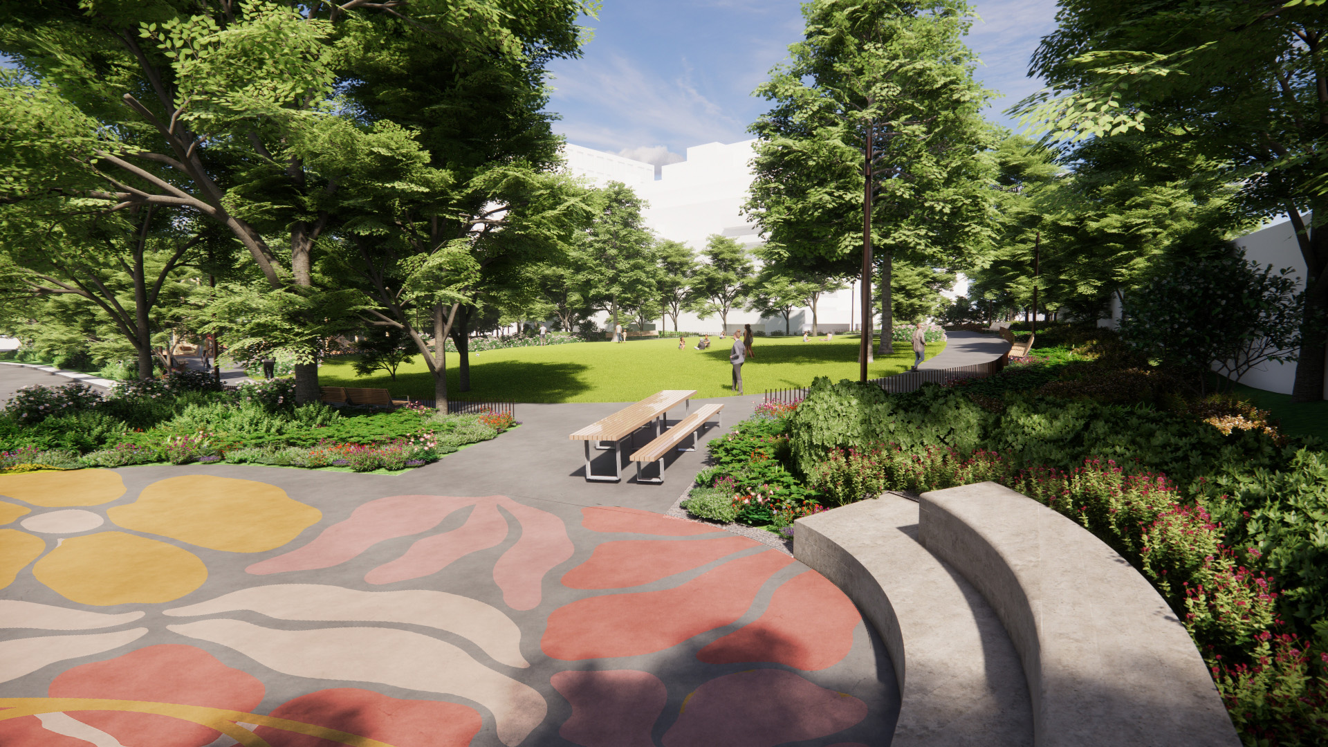 View from the multi-use court looking toward the north lawn. The court surface features a floral-inspired ground mural in shades of pink. The space is framed by low planting beds with seasonal flowering accents that add texture and colour, as well as two-tiered stone seating that provides informal gathering. In the background, a canopy of mature trees encloses the space and provides shade, while a looping pathway curves through the park around an open grassy lawn.