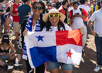 Two people in a crowd posing for a photo hold up a flag.