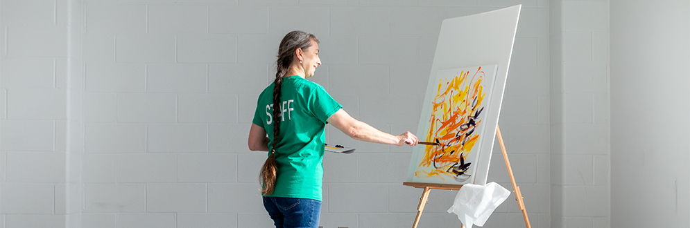 Person painting an abstract artwork on a canvas in a bright studio.