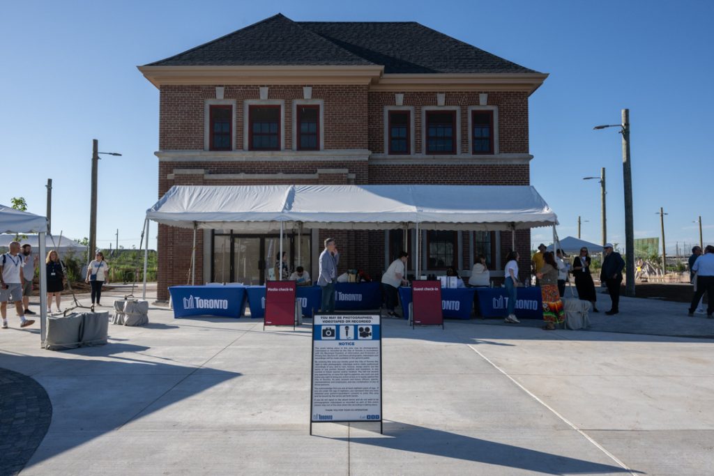 Historic fire hall with Toronto booth and tents in front and a photography notice sign.