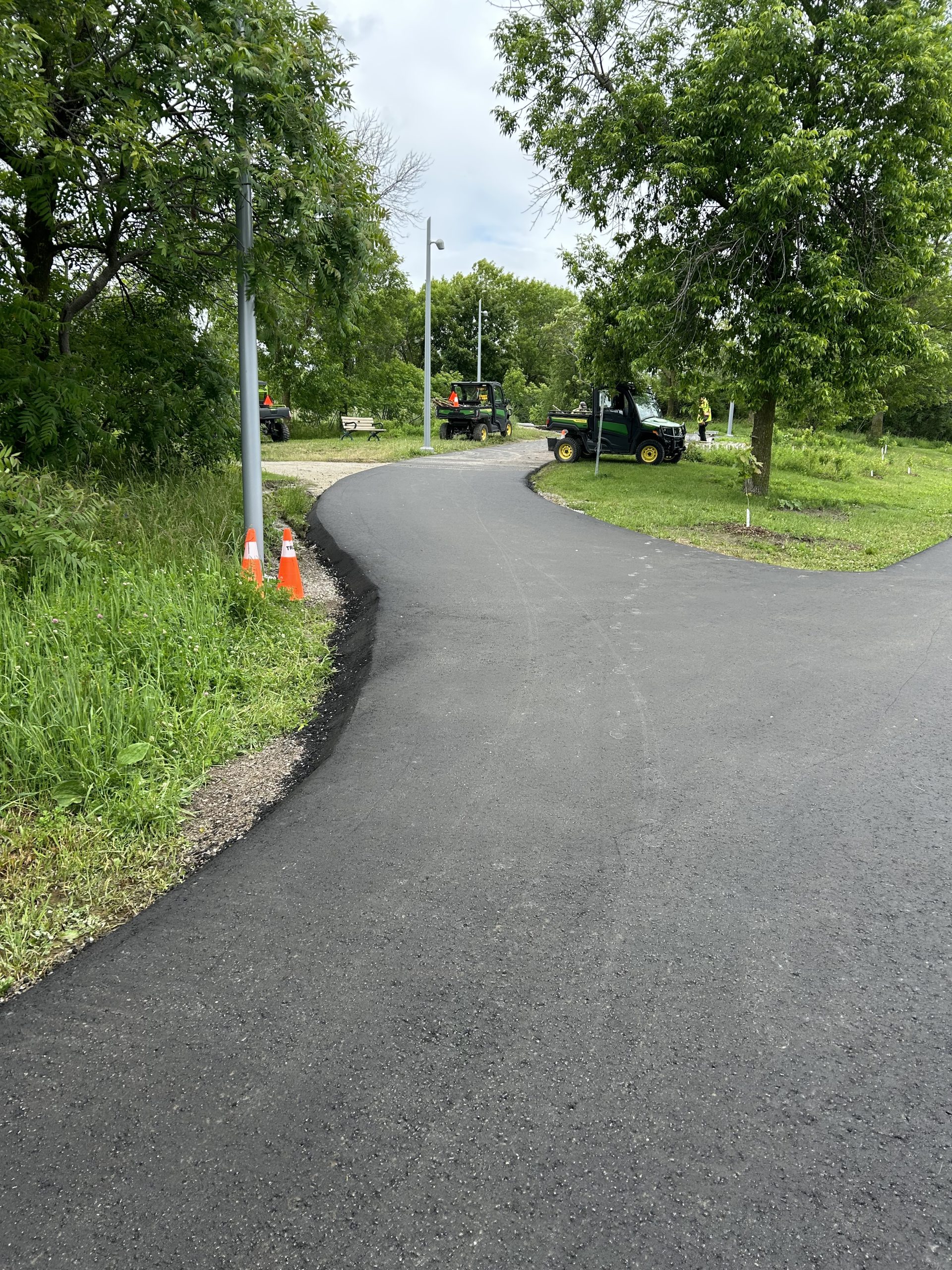 A new asphalt pathway with grass and trees on either side.