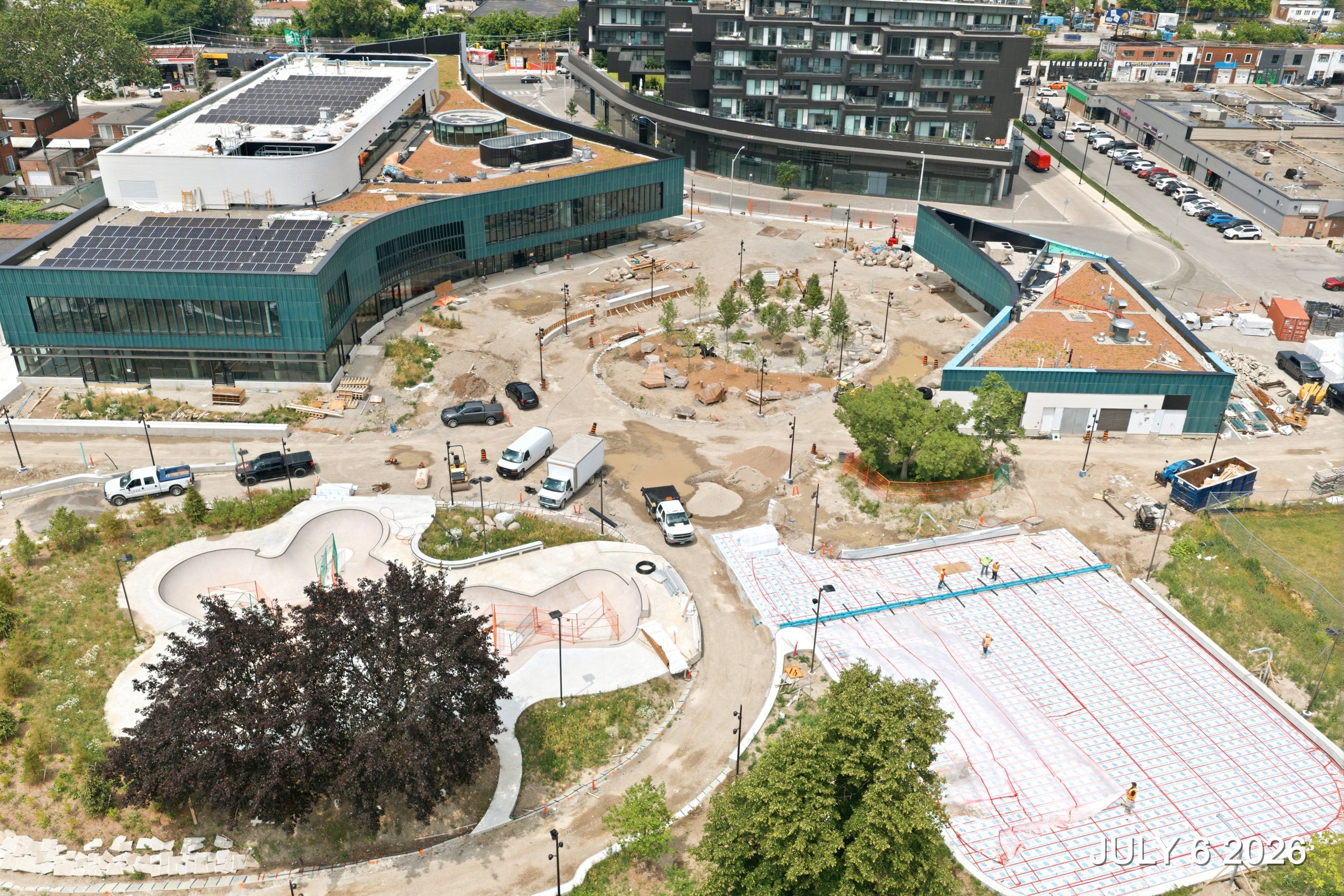 An aerial view of the construction site on July 6, 2026, showing work underway preparing for the outdoor rink concrete pour.
