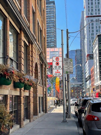 Street view showing the new regulatory sign mounted beside an existing parking sign on a utility pole.